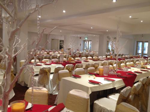 un gran salón de banquetes con mesas y sillas blancas en The Connaught Hotel Wolverhampton, en Wolverhampton