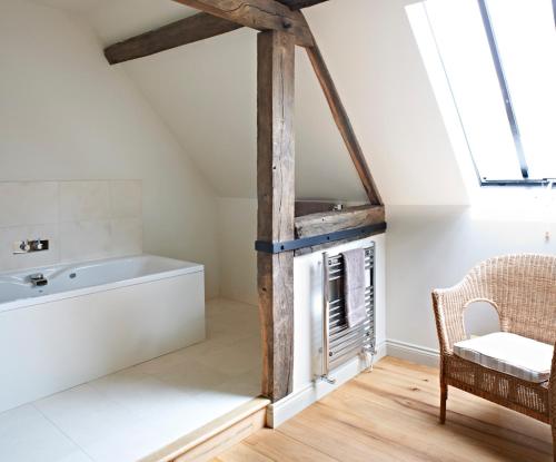 a bathroom with a bath tub and a chair at Manor Farm Courtyard Cottages in Hampstead Norris