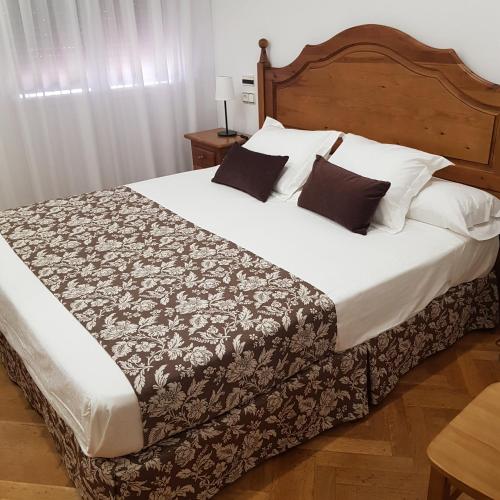 1 dormitorio con 1 cama grande con sábanas y almohadas blancas en Hostal La Parada, en Pedro Muñoz