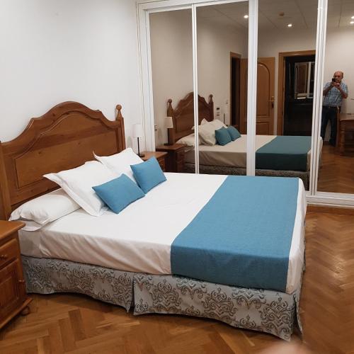 a bedroom with a bed with blue pillows and a mirror at Hostal La Parada in Pedro Muñoz