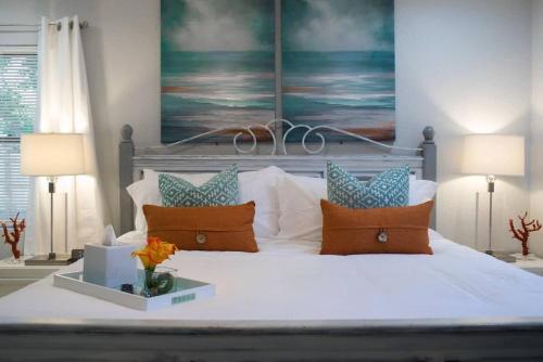 um quarto com uma cama branca com almofadas e um quadro em Sunset Oasis em Tampa