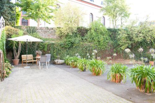 a patio with a table and an umbrella and plants at Weingut Johanneshof in Minheim