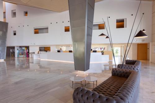 a lobby with two chairs and tables in a building at Hipotels Gran Playa de Palma in Playa de Palma