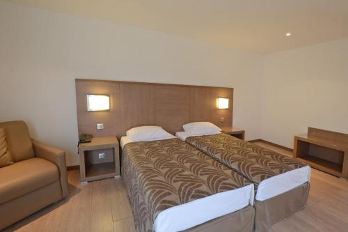 a hotel room with a large bed and a couch at Calvi Hôtel in Calvi