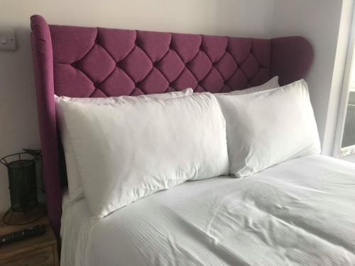 a bed with a purple head board and white pillows at The Reubens in Bedale