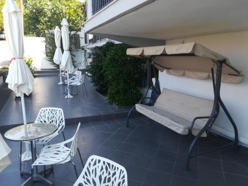 un patio con sillas, una cama, mesas y sombrillas en Villa Teo, en Kalamata