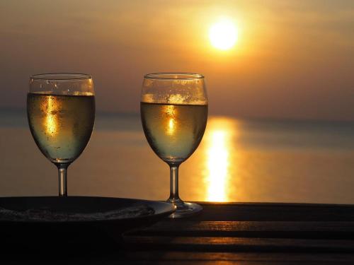 dois copos de vinho sentados numa mesa perto do oceano em O Little Tent de Koh Chang em Ranong