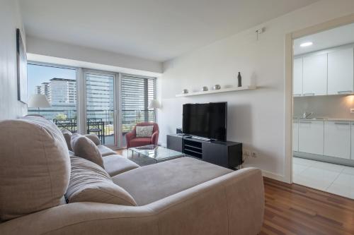 Una sala de estar con un sofá y un televisor. en Rent Top Apartments Beach-Diagonal Mar, en Barcelona