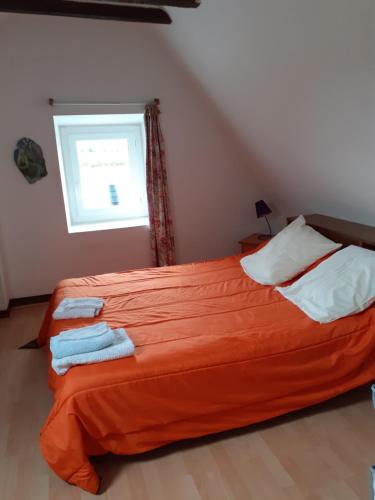 1 dormitorio con cama con sábanas de color naranja y ventana en Studio, en Pontacq