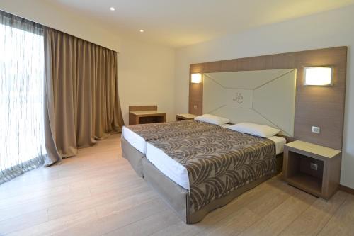 een hotelkamer met een bed en een groot raam bij Calvi Hôtel in Calvi