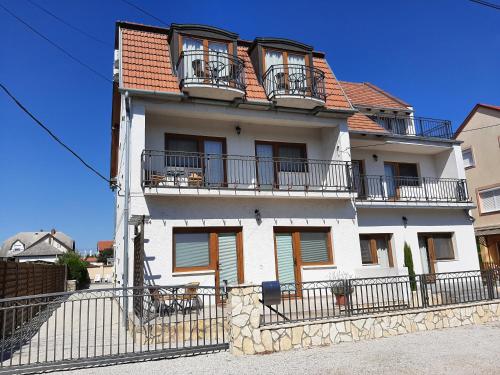 a white building with balconies and a fence at Família Apartmanház in Keszthely