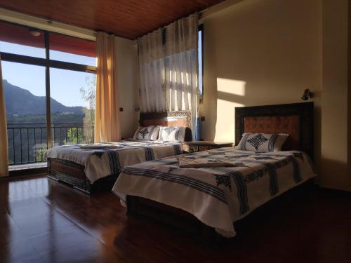 two beds in a bedroom with a large window at Merkeza Guest House in Lalībela