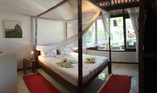 a bedroom with a canopy bed and a window at Refugios Parajuru - Casa Verde in Parajuru