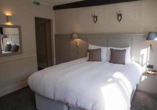 a bedroom with a large white bed with two pillows at The Kings Arms Hotel in Malmesbury