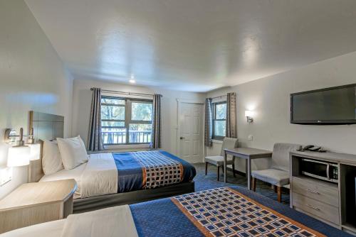 a hotel room with a bed and a flat screen tv at The Gunnison Inn at Dos Rios Golf Course in Gunnison