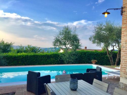 - une piscine avec une table et des chaises à côté dans l'établissement Villa Fiorenzani, à Radicondoli