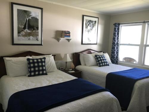 a bedroom with two beds with blue and white sheets at Highland Lake Resort in Bridgton