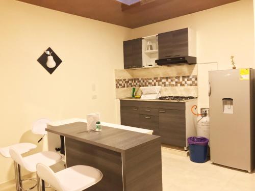 una cucina con frigorifero in acciaio inox e sedie bianche di Apartamento Santa Isabel a Santa Rosa de Cabal