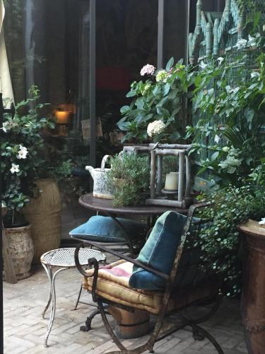 a bench with a table and lots of plants at La Maison Rousseau Chambre d'hôtes in Nîmes