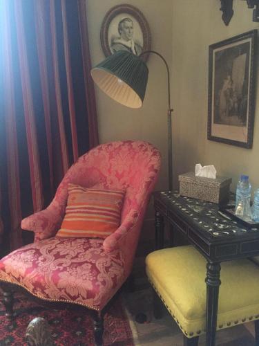 a room with a chair and a lamp and a table at La Maison Rousseau Chambre d'hôtes in Nîmes