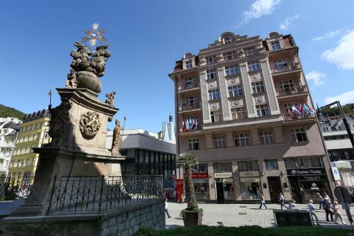 a statue in the middle of a city with a building at Art Deco WOLKER by ASTORIA Hotel & Medical Spa in Karlovy Vary