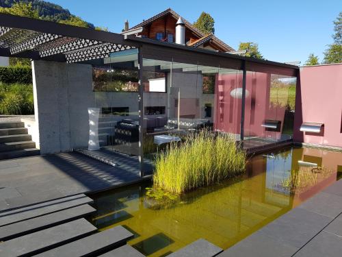 a glass house with a pond in the middle at Carrera - Ferienhaus mit Traumgarten (120m2) für max. 2 Personen in Valendas