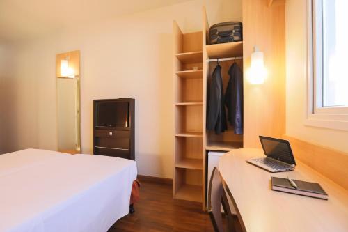 a hotel room with a bed and a laptop on a desk at ibis Montes Claros Shopping in Montes Claros