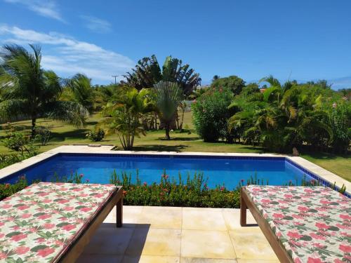 a swimming pool with two benches in front of a resort at Refugios Parajuru - Casa Graf in Parajuru