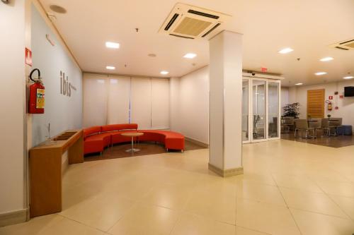 an office lobby with red chairs and a table at ibis Montes Claros Shopping in Montes Claros