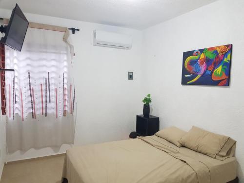 a bedroom with a bed and a painting on the wall at Casa en Mahahual cerca de la playa in Mahahual
