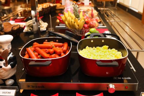 two pots of carrots and other vegetables on a counter at ibis Montes Claros Shopping in Montes Claros