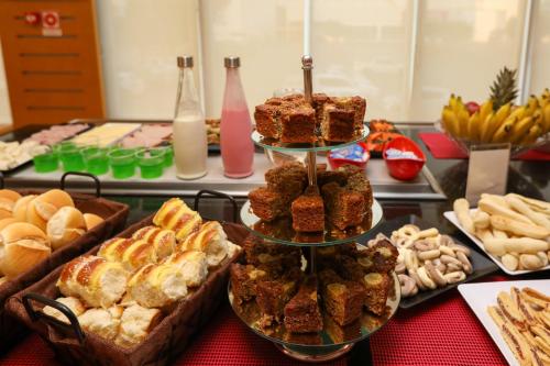a table topped with three tiers of pastries and other foods at ibis Montes Claros Shopping in Montes Claros
