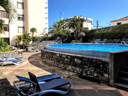a swimming pool with lounge chairs next to a building at Funchal Apartment, with pool in Funchal