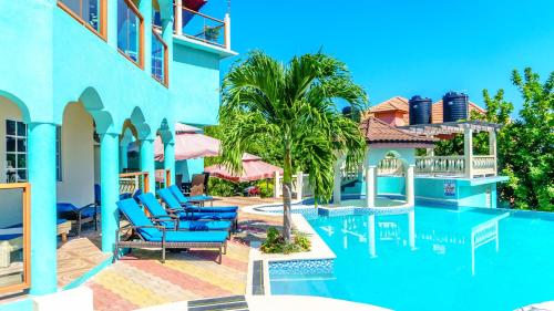 a pool at a resort with blue chairs and palm trees at Negril Sky Blue Resorts LTD in Negril