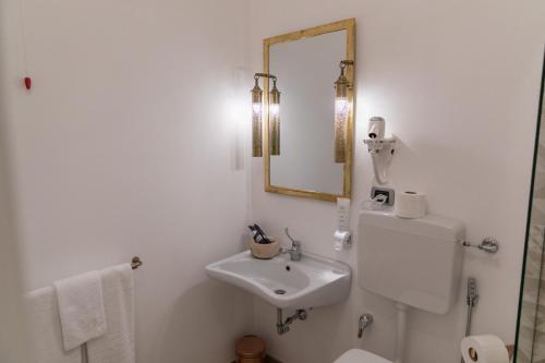 a white bathroom with a sink and a mirror at Love & Fama Hotel in Sabaudia