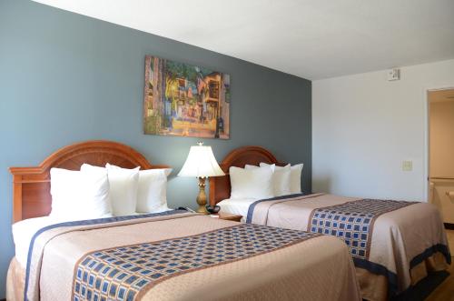 two beds in a hotel room with blue walls at Smart Stay Inn - Saint Augustine in Saint Augustine