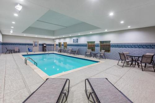 - une piscine avec des chaises et une table dans une chambre dans l'établissement La Quinta by Wyndham Houston East at Sheldon Rd, à Channelview