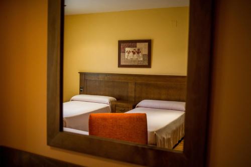 a mirror reflecting a room with two beds and a chair at Hostal Rural el Nacimiento in Deifontes