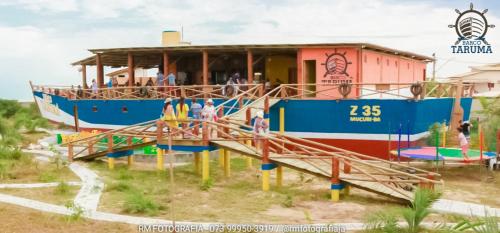 a blue and red boat with people standing in front of it at Pousada Taruma in Mucuri