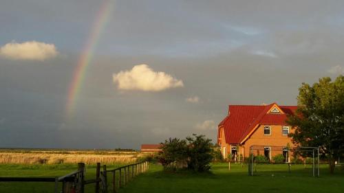 a rainbow in the sky over a house at Ferienhof Schild FeWo Bullerbü in Wangerland