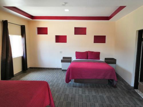 Habitación con cama con almohadas rojas. en Motel Ranchito, en Ensenada