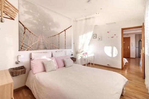 Dormitorio blanco con cama blanca y almohadas rosas en Atico Escapada a Granada, en Granada