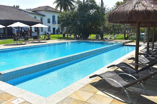 una gran piscina con sillas y sombrillas en Porto Grande Hotel & Convention, en São Sebastião