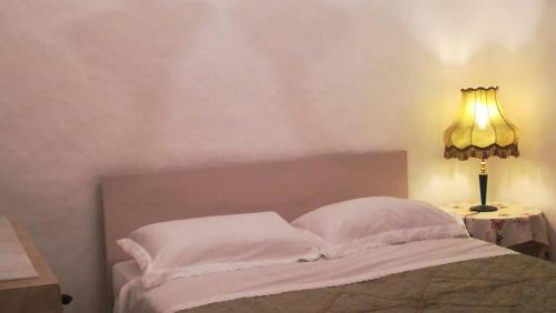 a bedroom with a bed with a lamp on a table at Trullo Le Tre Sorelle in Cisternino
