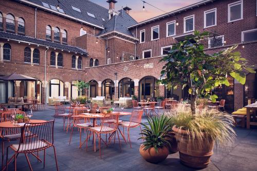 um pátio com mesas e cadeiras em frente a um edifício em The Anthony Hotel em Utrecht