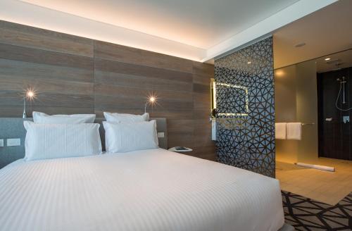 a bedroom with a large white bed and wooden wall at Pullman Sydney Airport in Sydney