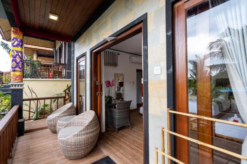 a balcony with wicker chairs and a glass door at Breeze Villa in Nusa Lembongan