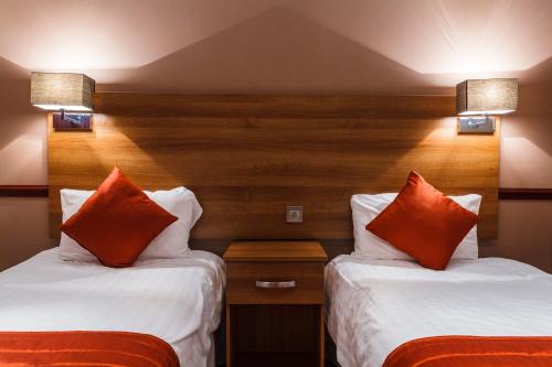 two beds in a hotel room with orange pillows at Griffin Inn in Newquay