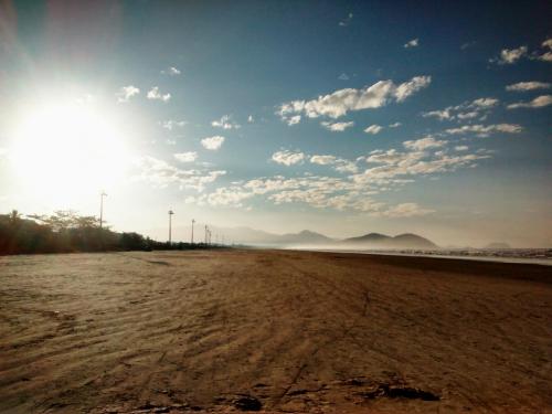 a sandy beach with the sun in the sky at Apartamento Boraceia 200 metros da praia, com ar condicionado in Bertioga