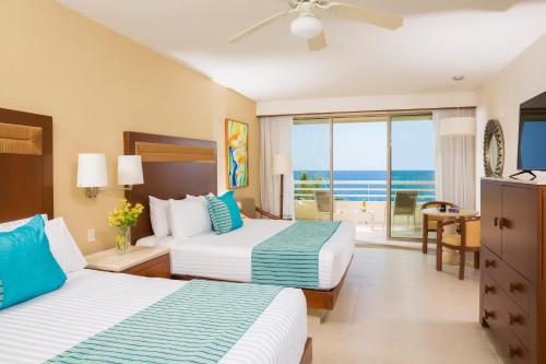 two beds in a hotel room with a view of the ocean at GR Solaris Lighthouse - All Inclusive in San José del Cabo